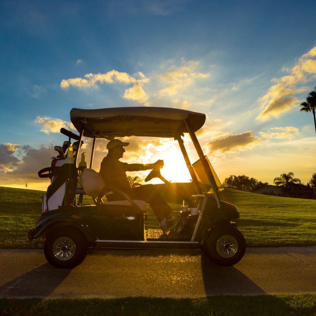 man driving his golf course at sunrise